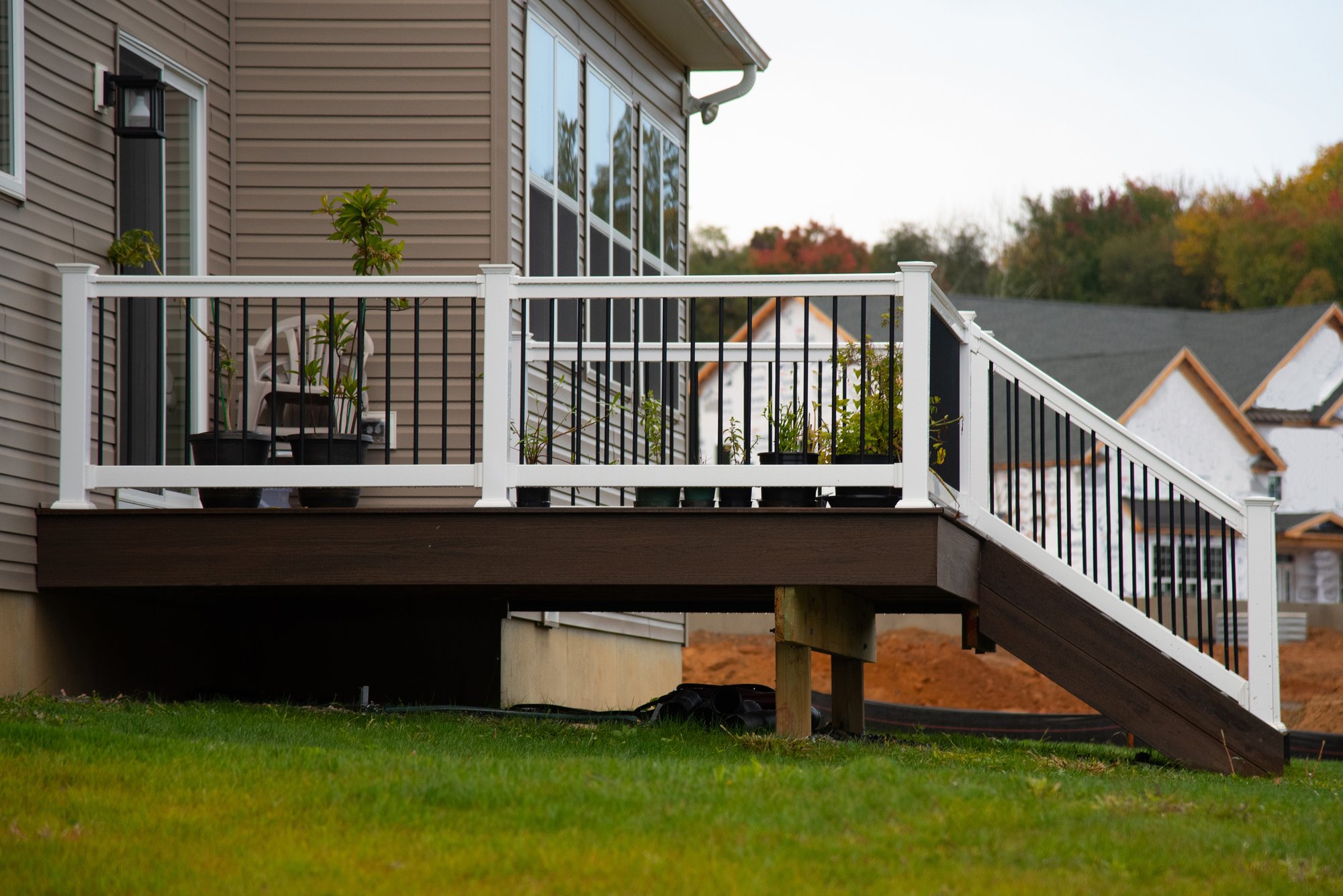 Dark composite deck with white railing, black balusters, and stairs down to the lawn