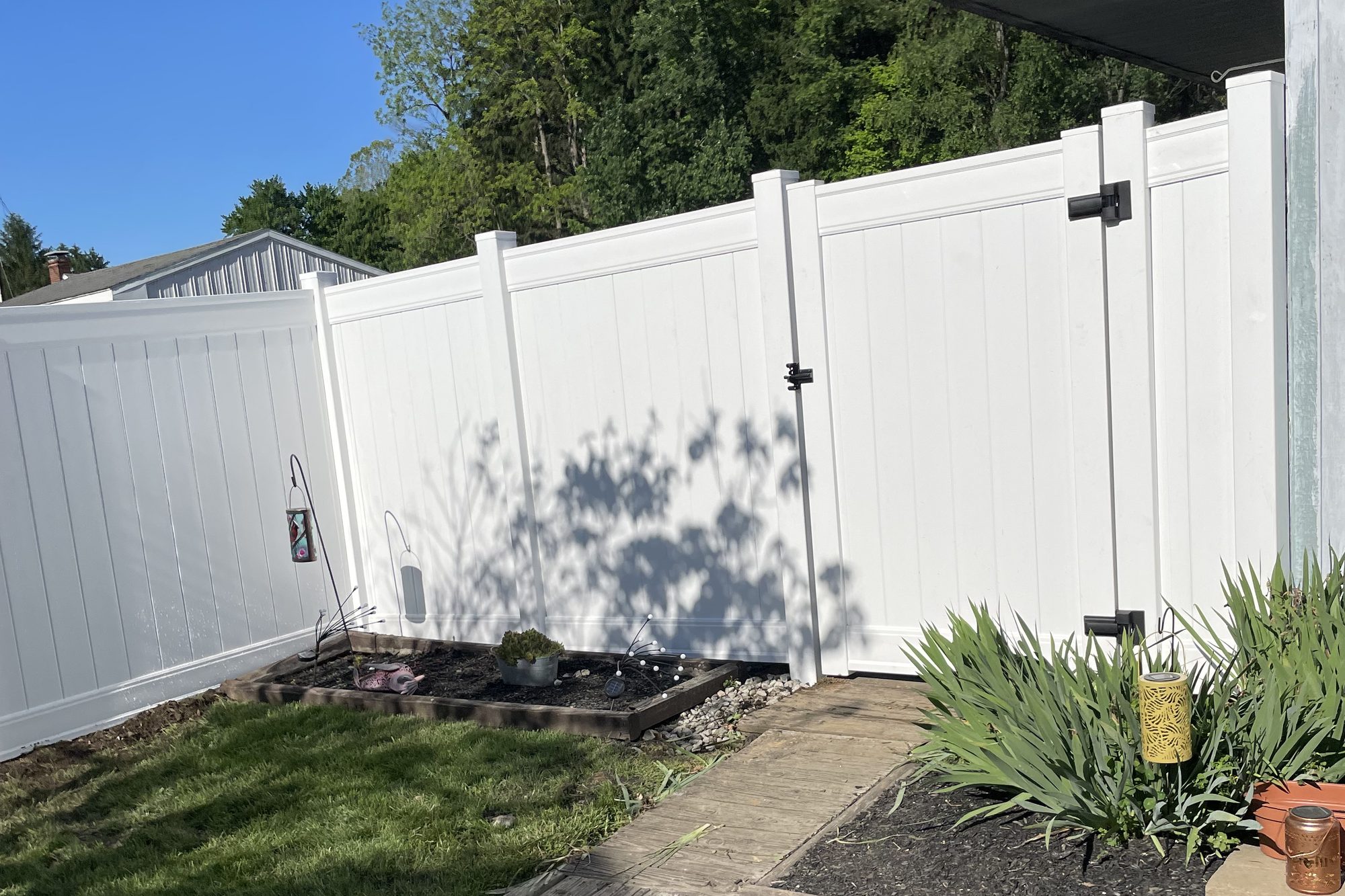 White vinyl privacy fence with a matching gate beside a house and garden
