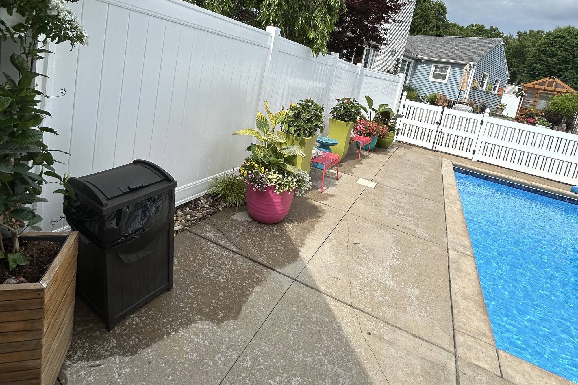 White vinyl privacy fence along a concrete pool deck with planters