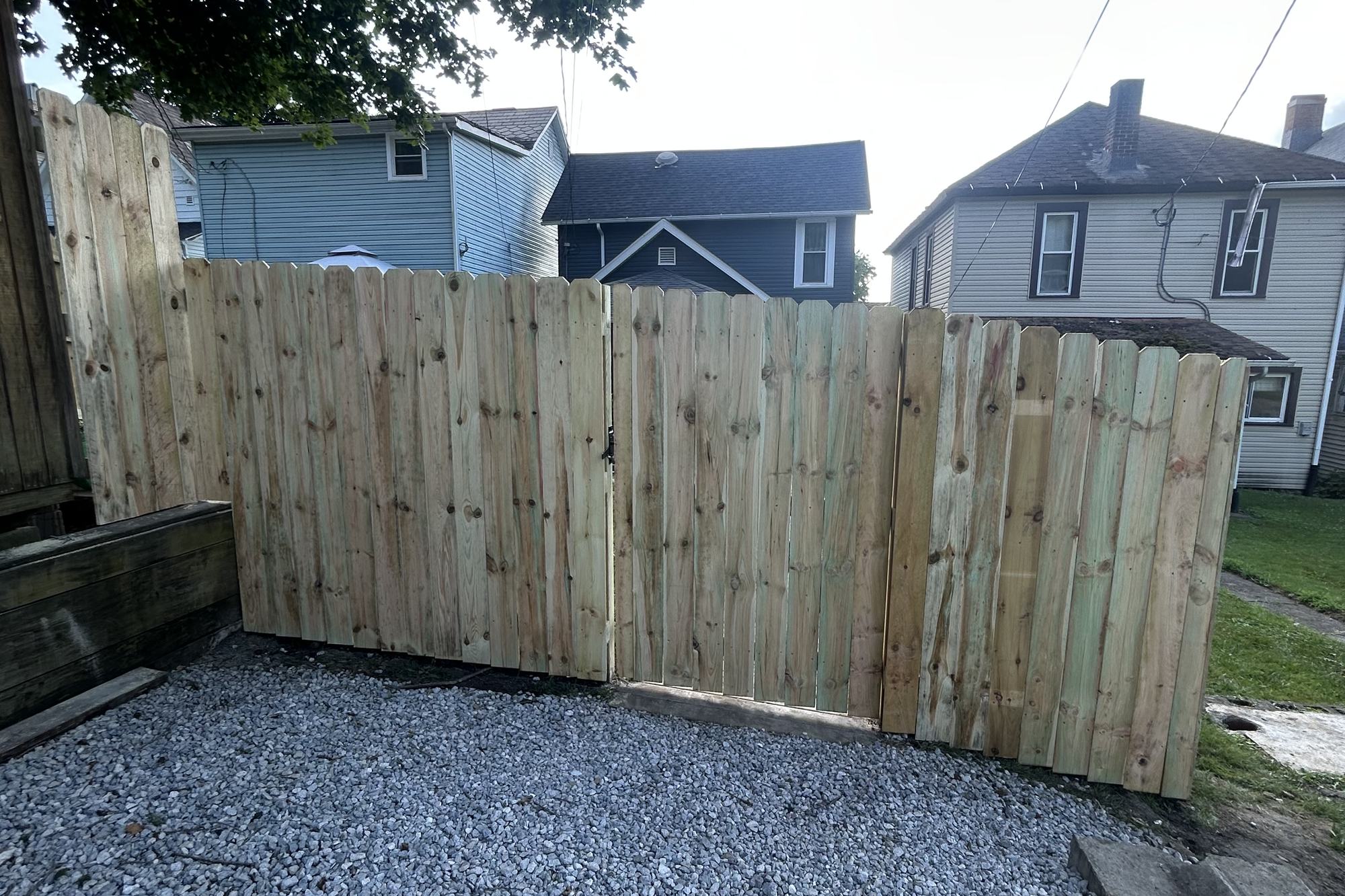 Wood privacy fence with a double gate over a gravel pad